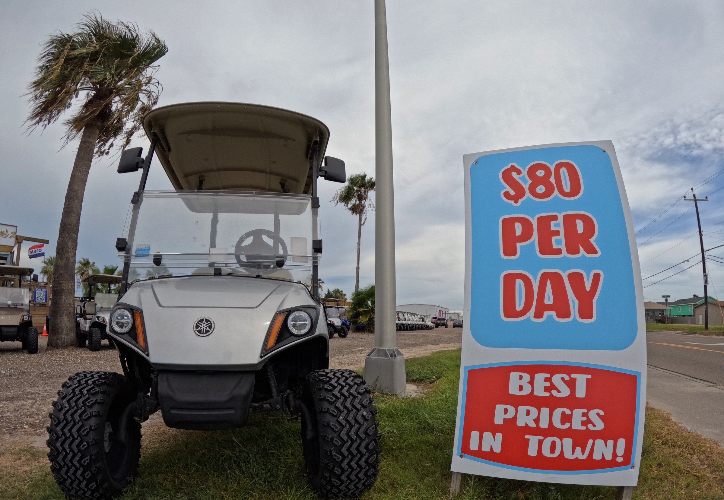 Silver Yamaha golf cart at Peyton's with $80 per day best prices sign (Port Aransas)