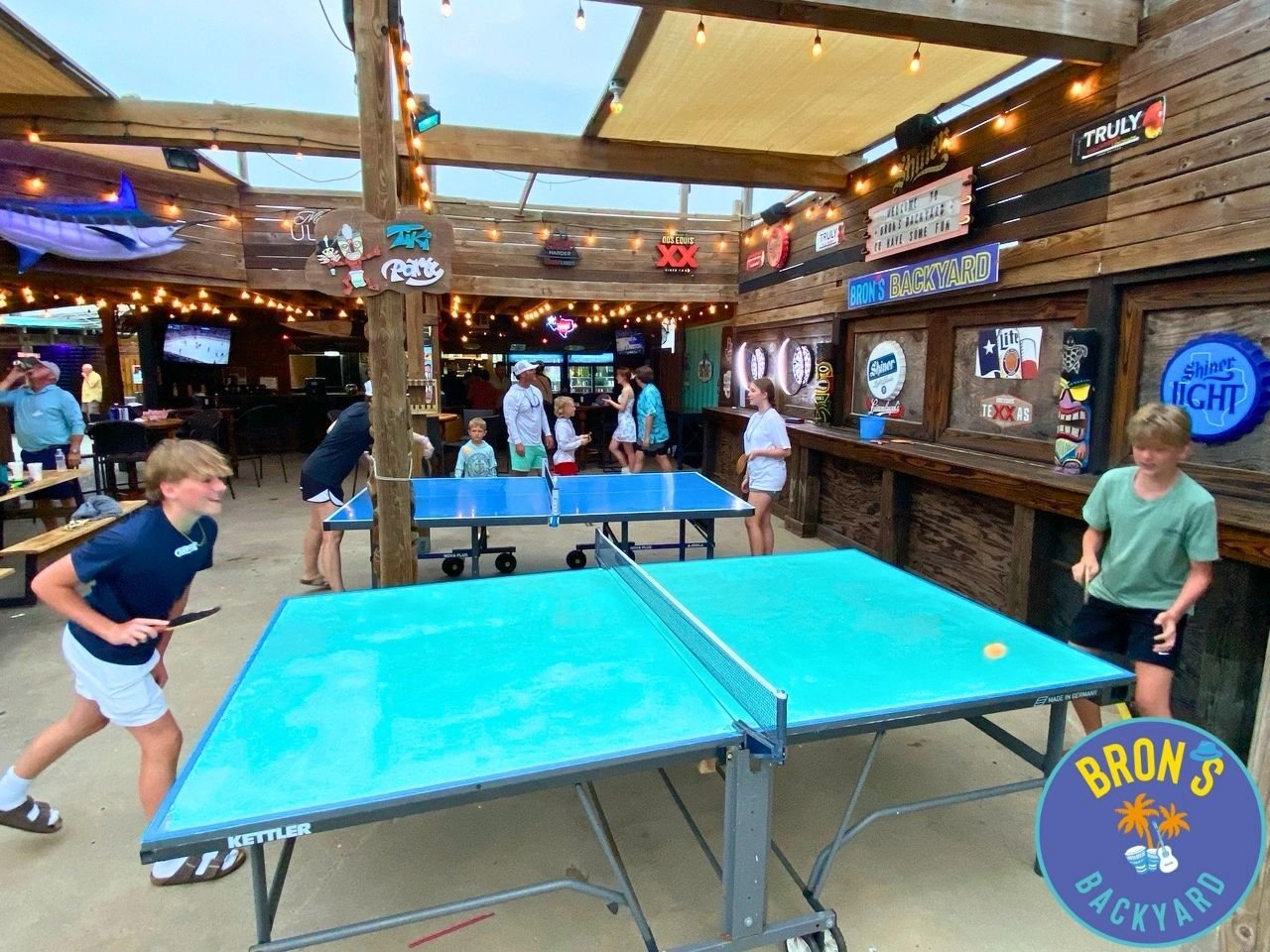 Bron’s Backyard patio on E Avenue G — covered hang, ping pong, and yard games