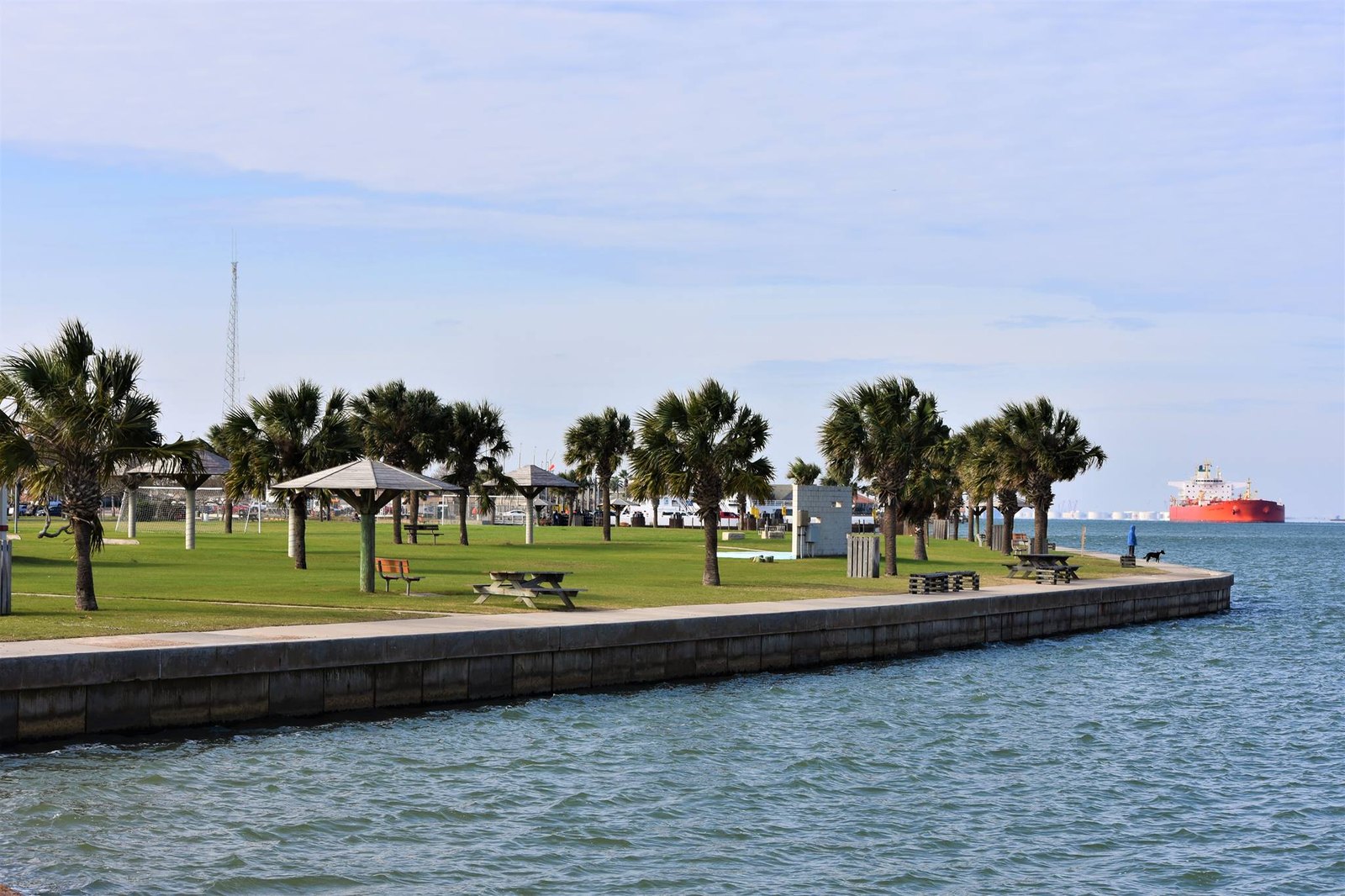 Roberts Point Park on the Port Aransas ship channel, with picnic lawns and a cargo ship passing